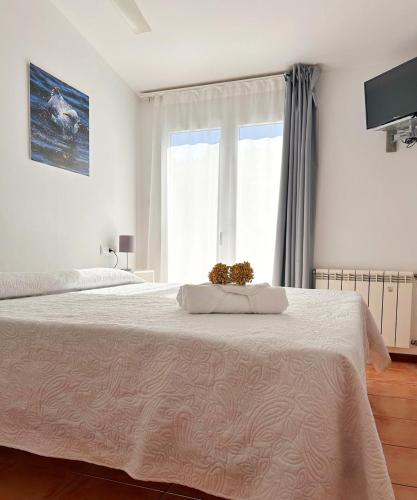 a white bedroom with a large bed and a window at Hotel Can Pepin in Cadaqués