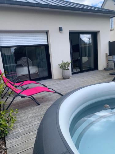 une terrasse avec un bain à remous et une chaise à côté d'une maison dans l'établissement LE REFUGE DE LA BAIE, à Beaussais sur Mer