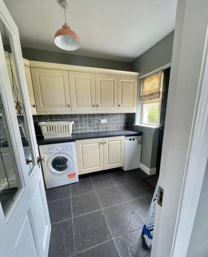 a kitchen with white cabinets and a washer and dryer at Conree Lodge in Castlemaine