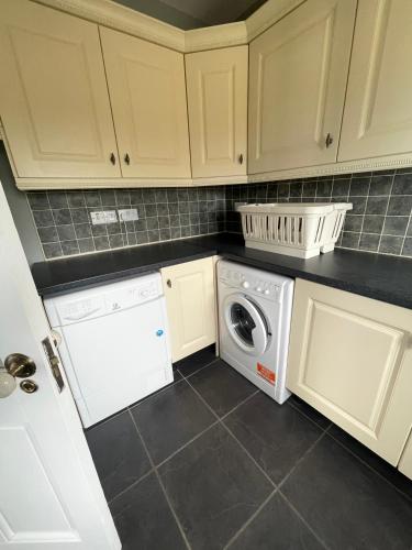 a kitchen with white cabinets and a washer and dryer at Conree Lodge in Castlemaine