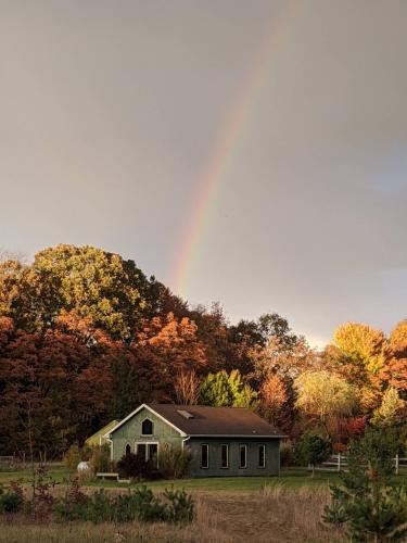 a rainbow over a house in a field with trees at Ancient Oak Sanctuary Rural getaway, walking paths in Grand Junction