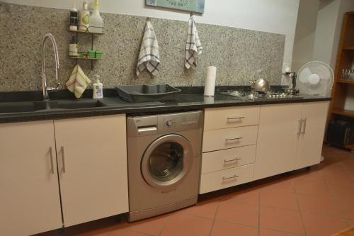 a kitchen with a sink and a washing machine at Pender House Cottage Melrose in Johannesburg