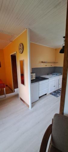 une cuisine avec une horloge sur un mur jaune dans l'établissement Le LILAS, à Éguzon-Chantôme