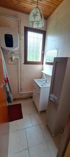 ein kleines Bad mit einem Waschbecken und einem Fenster in der Unterkunft Le LILAS in Éguzon-Chantôme