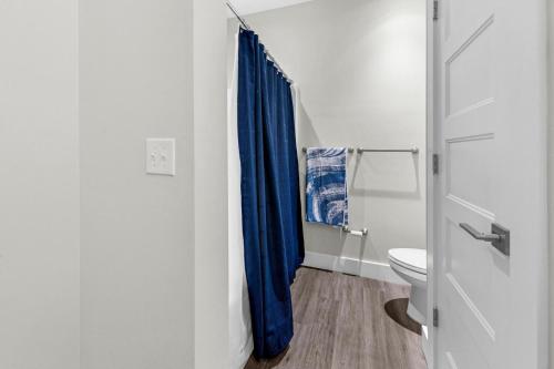 a bathroom with a blue shower curtain and a toilet at Completely Coastal Spacious townhome with Harbor views a Dock and community Pool in Fort Walton Beach