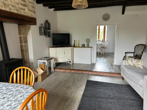 un salon avec un canapé et une télévision dans l'établissement La Maison Mignonne, à Azerables