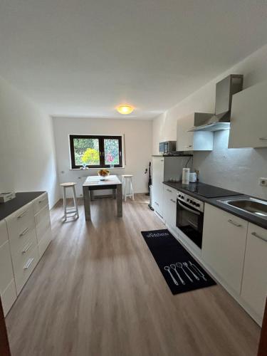 a kitchen with white cabinets and a table in it at Ferienwohnung Mittenaar in Mittenaar