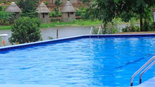 a large blue swimming pool with a river in the background at Loginecoresort in Lukunyu
