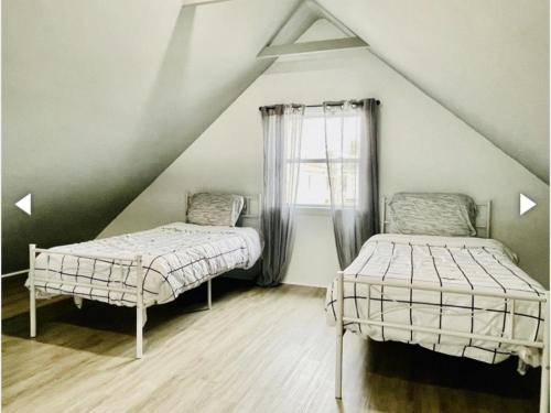 2 łóżka w pokoju na poddaszu z oknem w obiekcie Patel w mieście Beach Haven