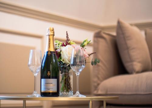 a bottle of wine and two glasses on a table at Hôtel Château Héloïse in Mérélessart