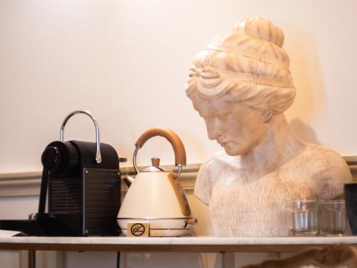 a statue of a woman on a table with a tea kettle at Hôtel Château Héloïse in Mérélessart