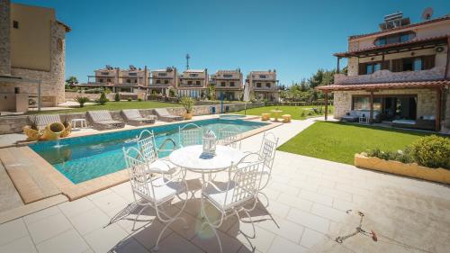 a patio with a table and chairs next to a swimming pool at Zeus Sea View Villa with Private Pool, Afytos in Afitos
