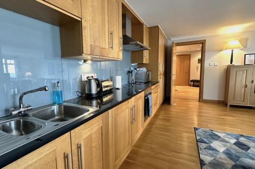 a kitchen with a sink and wooden cabinets at No2 The Links Apartment, Brora in Brora