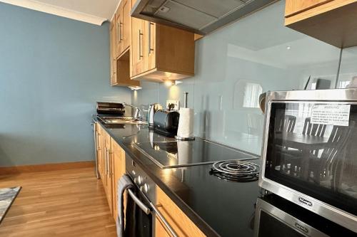 a kitchen with a stove and a microwave at No2 The Links Apartment, Brora in Brora