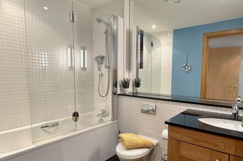 a bathroom with a shower and a toilet and a sink at No2 The Links Apartment, Brora in Brora