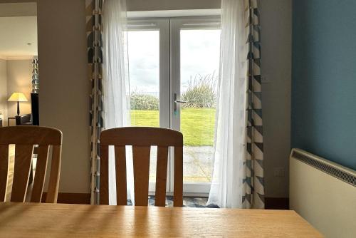 a dining room table with two chairs and a window at No2 The Links Apartment, Brora in Brora