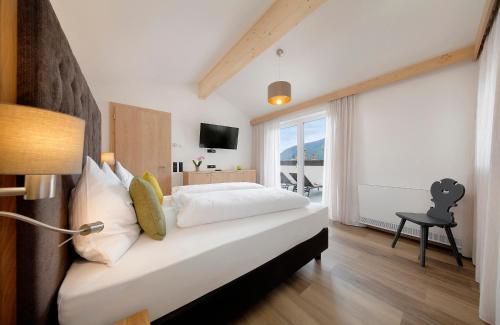 um quarto com uma cama e uma grande janela em Appartement-Hotel Anthea em Tirolo