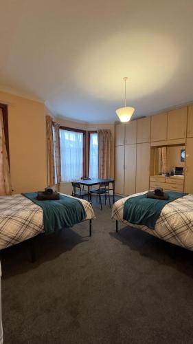 a hotel room with two beds and a table at 25 Minutes to Central London Rooms 35 in London