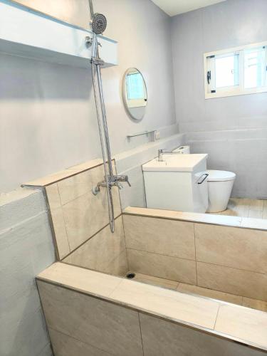 a bathroom with a shower with a toilet and a sink at Xinyuanbao Shangshi Homestay in Donggang