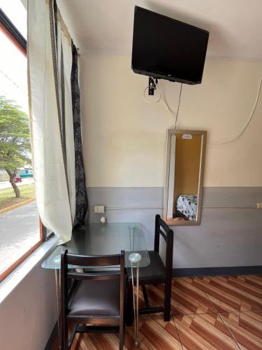 Habitación con mesa y TV en la pared. en Condominio Confortable, en Talara