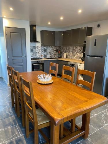 une cuisine avec une table en bois avec des chaises et un réfrigérateur dans l'établissement L’echauguette, à Fermanville