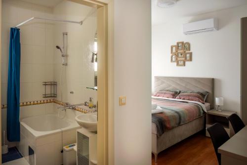 1 dormitorio con cama, bañera y lavamanos en Apartments4You en Vodice