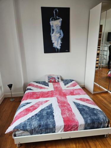 - un lit avec une couette rouge blanche et bleue dans l'établissement Une chambre chez Christina 250m de la plage, à Royan