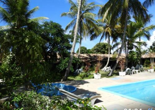 un complexe avec une piscine et des palmiers dans l'établissement Pousada Verdes Mares, à Santa Cruz Cabrália