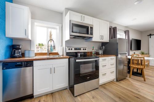 a kitchen with white cabinets and stainless steel appliances at Downtown Newly Remodeled Apartment AC Beach Restaurants Breweries Nightlife in Traverse City