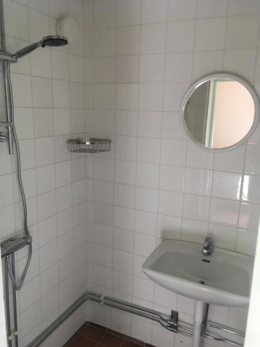 Baño de azulejos blancos con lavabo y espejo en Enköping Cottage en Enköping