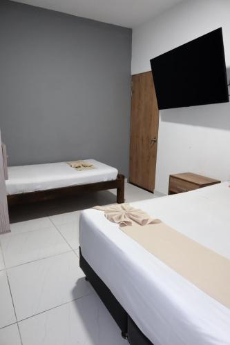 a room with two beds and a flat screen tv at Hotel París in Villeta