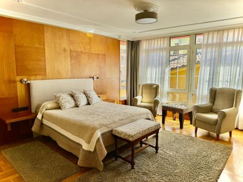 拉斯阿雷納斯的住宿－Hotel La Rivera，一间卧室配有一张床和两把椅子