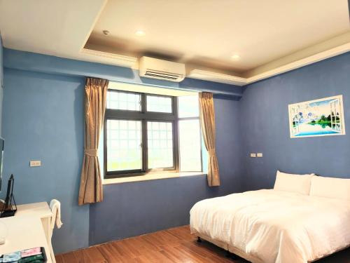 a blue bedroom with a bed and a window at Xinyuanbao Shangshi Homestay in Donggang