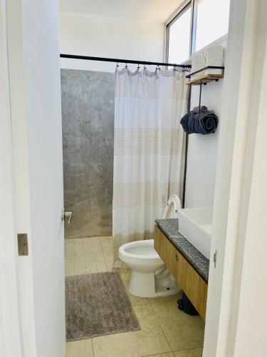 a bathroom with a toilet and a shower curtain at Charming and Cozy Condo San Blas in Puerto Vallarta