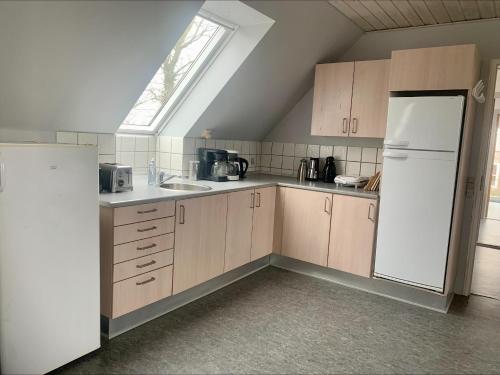 a kitchen with a white refrigerator and a window at Kongshøjgaard in Farsø