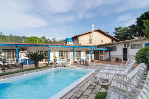 uma casa com piscina e cadeiras brancas em Garden 437 Suítes em Florianópolis
