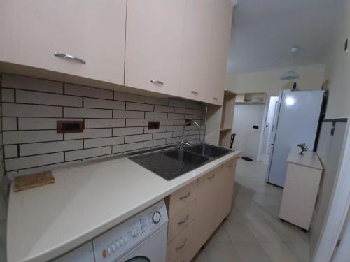 a white kitchen with a sink and a refrigerator at Lovely appartament,1-D in Tirana