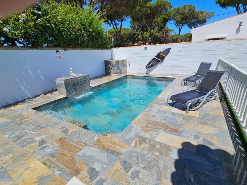 una piscina con 2 sillas y una sombrilla en Casa piscina, en Chiclana de la Frontera