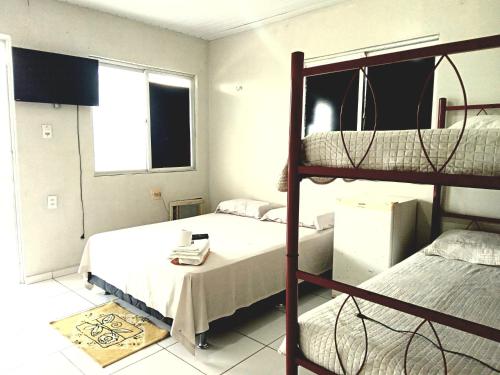 a bedroom with two bunk beds and a table at Pousada Mazolas in Salinópolis