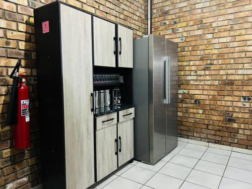 a kitchen with a refrigerator and a brick wall at Core-Lodgings in Nigel