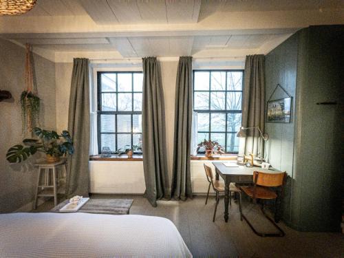 a bedroom with a desk and a bed and a table and window at Bed & Breakfast [H]eerlijk! in De Kwakel