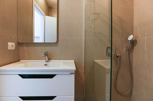 y baño con lavabo y ducha con espejo. en Superb Studio (2min Beach) *Parking + Sea View, en Himare