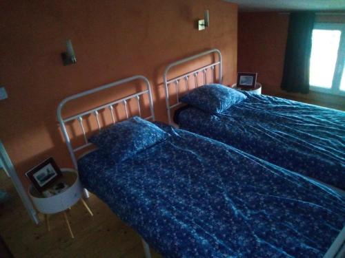 a bedroom with two beds with blue sheets and a window at Vachement bien ! in Saint-Nicolas-de-la-Haie