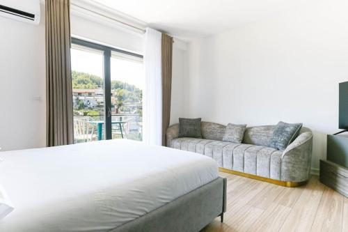 Habitación blanca con cama y sofá en Superb Studio (2min Beach) *Parking + Sea View, en Himare
