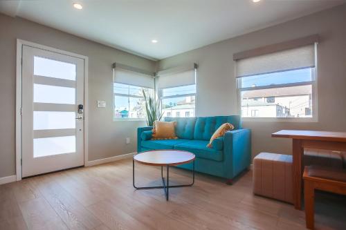 a living room with a blue couch and a table at Ocean Beach Retreat, 3BR Newly Remodeled, Steps to Beach and Boardwalk in San Diego