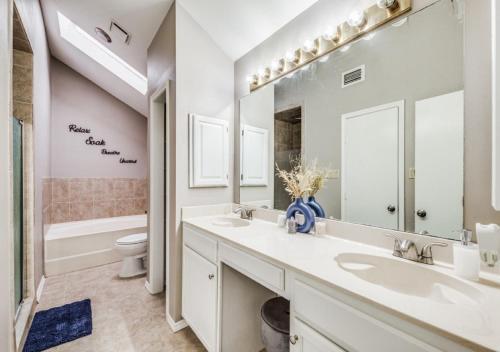 uma casa de banho com 2 lavatórios, um WC e um espelho grande em 4 Bedroom Suburban Dream House - SeaWorld-6Flags-MedCenter - Sleeps 10 em San Antonio