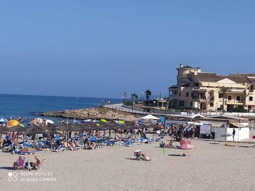 eine Gruppe von Menschen mit Sonnenschirmen an einem Strand in der Unterkunft La Florida Catalina House in Orihuela