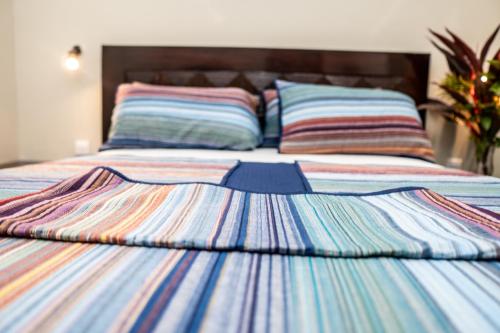 a bed with a colorful striped comforter on it at ZURI Town Homes in Kololi