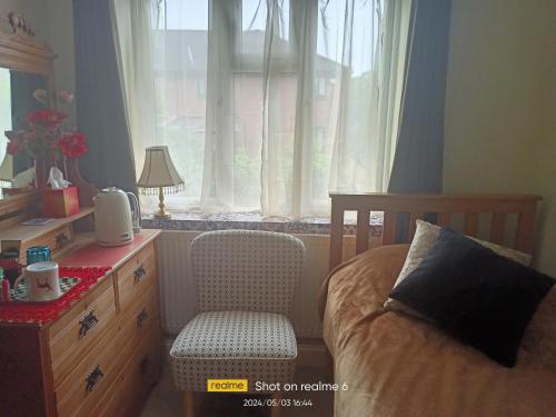 Goldy's place in E17 Room2 في لندن: غرفة نوم بسرير وكرسي ونافذة
