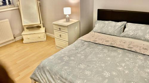 ein Schlafzimmer mit einem Bett, einer Kommode und einer Lampe in der Unterkunft Magnolia in Peterborough